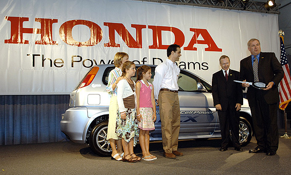 Senior Vice President of American Honda Motor Co., Inc, John Mendel, right, presents a symbolic key to the Spallino family for their 2005 Honda FCX, an advanced hydrogen-powered fuel cell vehicle, during a news conference introducing the vehicle, Wednesday, June 29, 2005 in Los Angeles. Honda, the only automotive manufacturer to certify its fuel cell vehicle for regular daily use and the first to offer its technology to an individual customer, is leasing to the Spallinos, the world's first individual customers to the revolutionary vehicle, for a period of two years. Jon Spallino, center, with wife Sandy and daughters Anna, 9, in pink, and Adrianna, 10. Second from right is Dr. Alan Lloyd, Secretary of the California Environmental Protection Agency.
