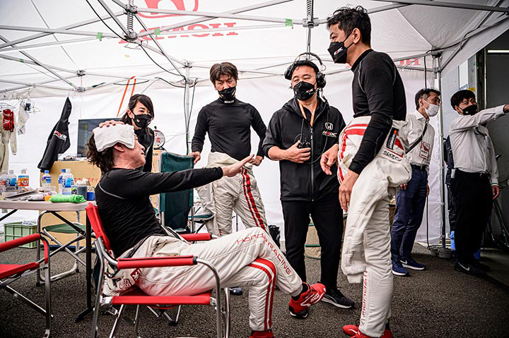 After his stint, an exhausted Kakinuma sits down to rest, but continues exchanging information with the other drivers.