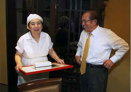 Tokyo Graphic Designers president Tsugio Ogata presents a commemorative plaque to the soba shop owner, who was a little girl at the time that first ad debuted