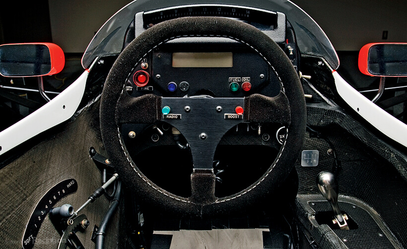 The cockpit has an old-fashioned feel. Shift lever on the right and stabilizer adjustor on the left. The red button is boost for overtaking, and the blue button is the radio.