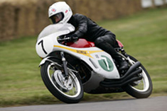 The RC166, thunders up the hill climb course with its clear exhaust sound, and riding form exactly as it would have been at the time. The rider is Stewart Graham.