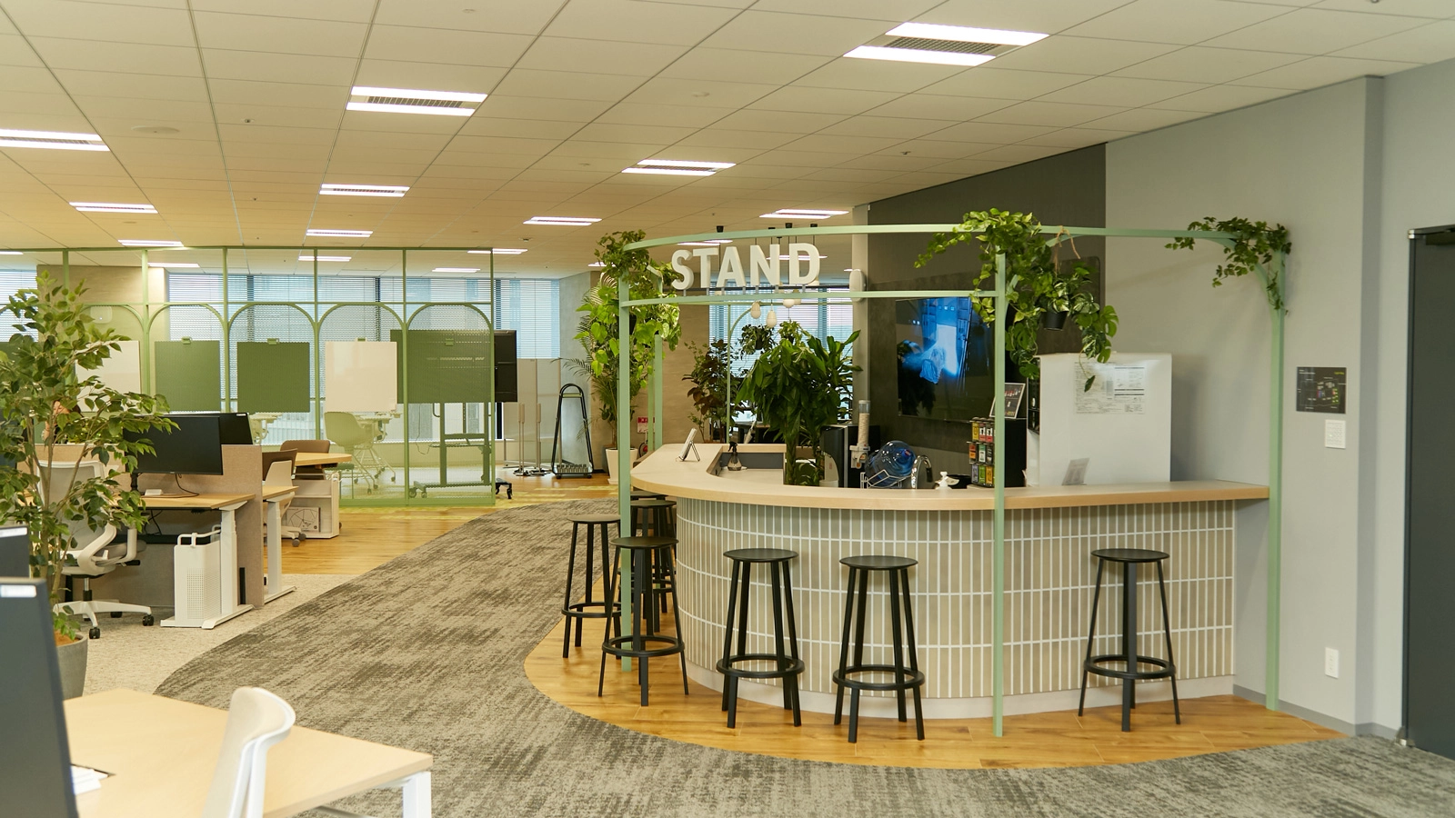 さらに奥へと進むと、デスクエリアが出現。黄色やグリーンなどの明るい色が使われ、生き生きとした印象。このカフェSTANDでも、会話のきっかけをつくるために週替わりで本を1冊だけ置き、さまざまな人と自然に交流できるようにしています