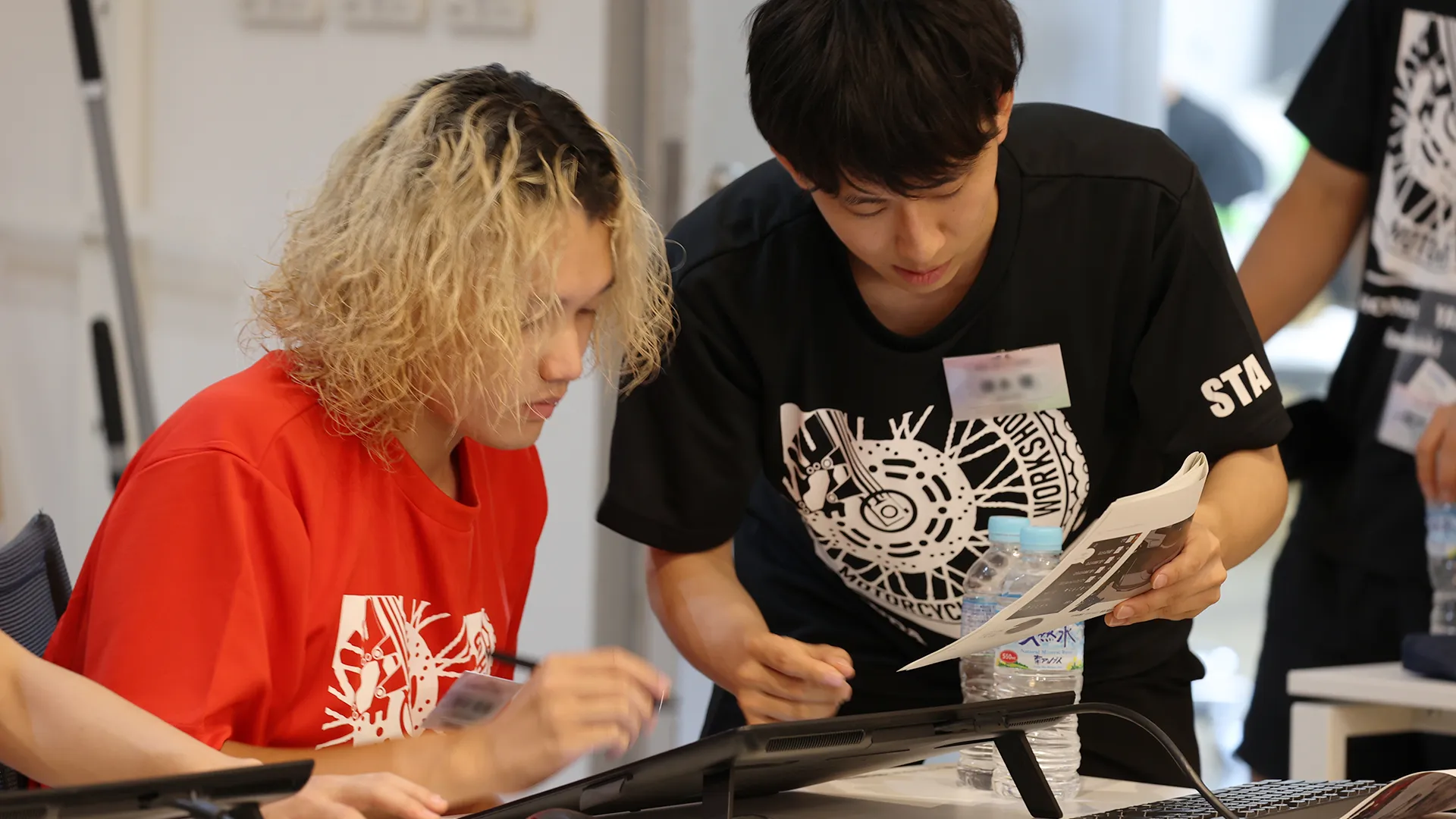 スケッチの手本を見ながら描き方を確かめる学生たち