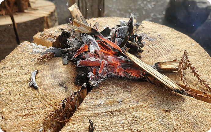 しばらく中央で細かい枝葉を追加しながら焚き火すると、中央の熾火から丸太ストーブに火が回ります。